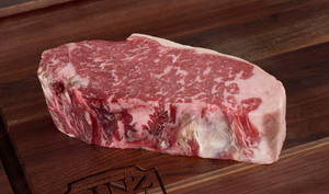 Pictured is an uncooked Linz Heritage Angus dry aged boneless strip steaks on a cutting board.