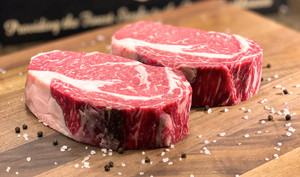 Pictured is 2 uncooked Linz Heritage Angus boneless dry aged on a cutting board, wet aged for 35 days and dry aged for 28 days