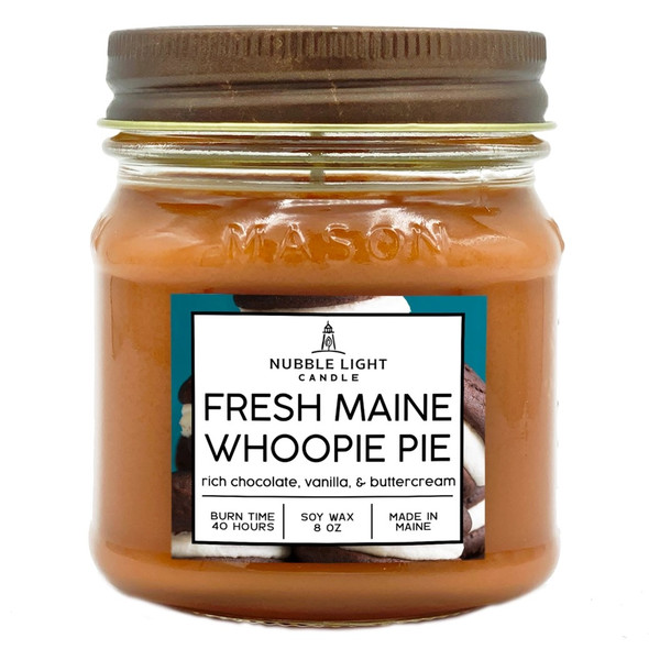 a candle in a clear glass mason jar with light brow wax and a label that reads "Maine Whoopie Pie" against a white background